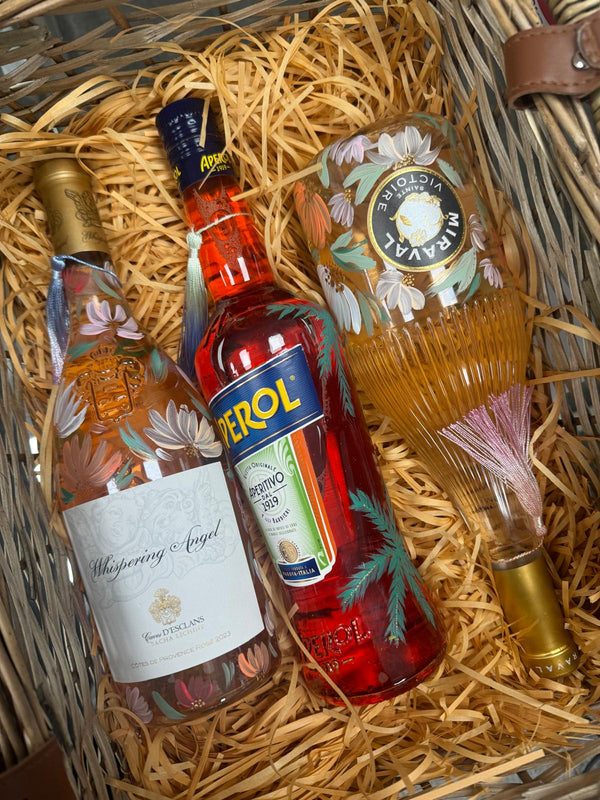 Three bottles of alcohol in a woven basket with personalised hand painted decorative elements